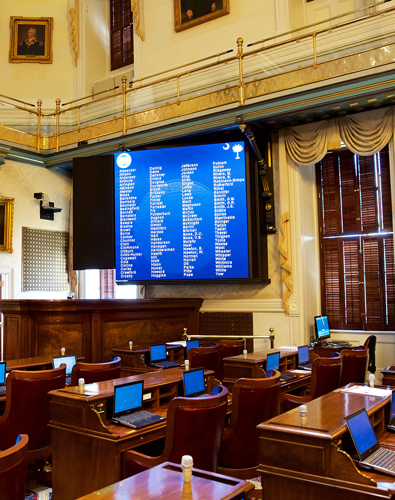 The room’s “scoreboards” can be used to displays voting results and are flanked by the main P.A. speakers. 