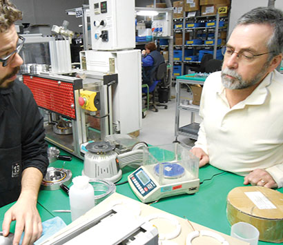Steve Hutt observes an 18Sound team member hand-building one of their high-performance transducers.