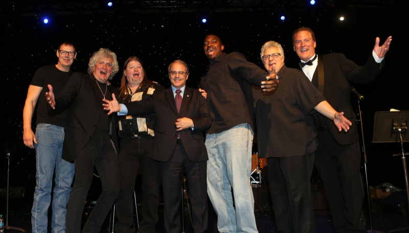 Members of the celebrity-studded audience pose with one of the evening’s auction winners. Pictured L to R: Michael Derosier, drummer for Heart; Jeff Kathan, drummer for Spike and the Impalers and former drummer for Paul Rodgers (Bad Company); Mike Kearse, local Seattle musician; Washington State’s Lt. Governor Brad Owen; Greg Scruggs, Seattle Seahawks defensive end; Scott Batchelder, drummer for the Sonics; and Mark Christopher, Seattle radio/TV personality. (c) Corky Trewin