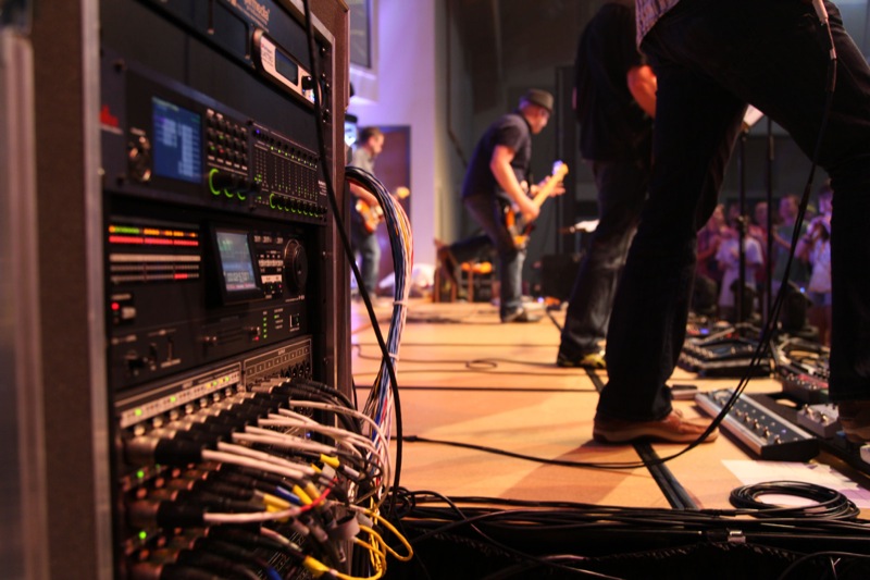 A band performs at a recent event in Denver, with Nebraska-based firm Inspirmedia providing A/V services and components, including Roland Professional A/V components such as the R-1000 48-Track Recorder/Player and S-2416 Digital Snake Stage Unit, both visible in the rack. (c) Inspirmedia 2015