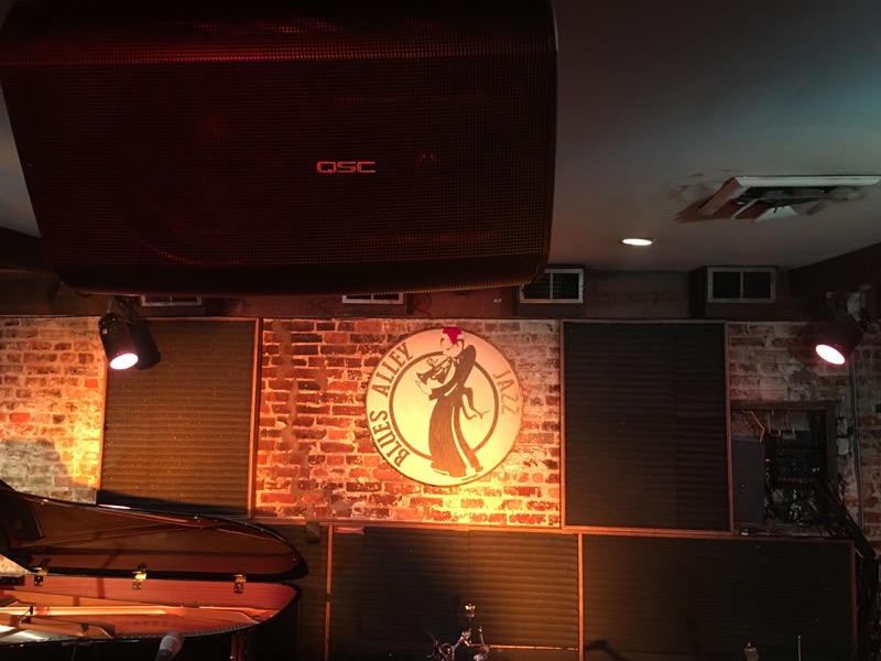 : A view of the stage at legendary Washington, D.C. venue Blues Alley, with one of five QSC AD-S12 (2-way 12-inch) loudspeakers visible – part of the extensive AV upgrade sourced through Guitar Center Professional. About Guitar Center Professional